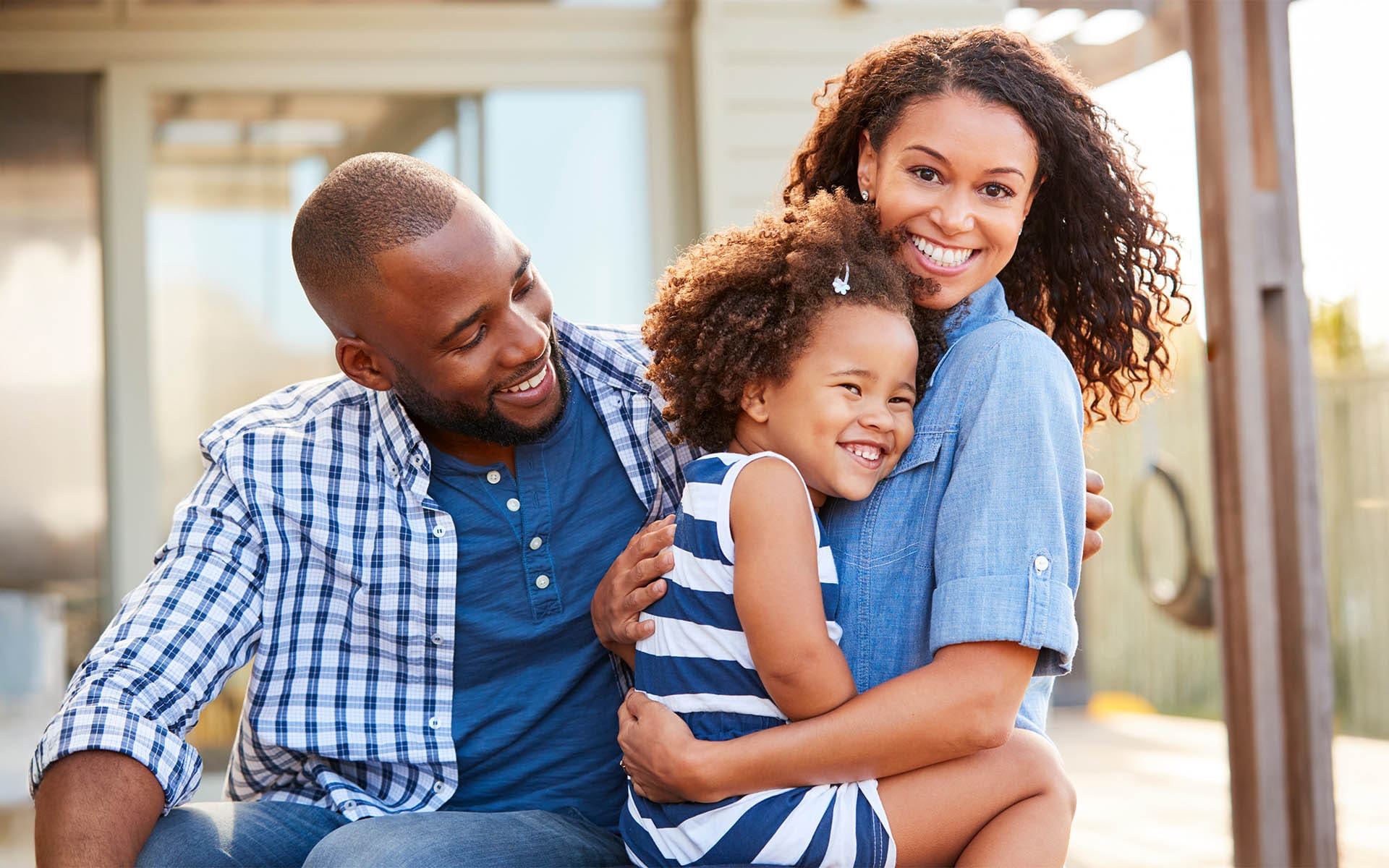 Homepage - Family Embracing Outdoors Smiling to Camera Outside